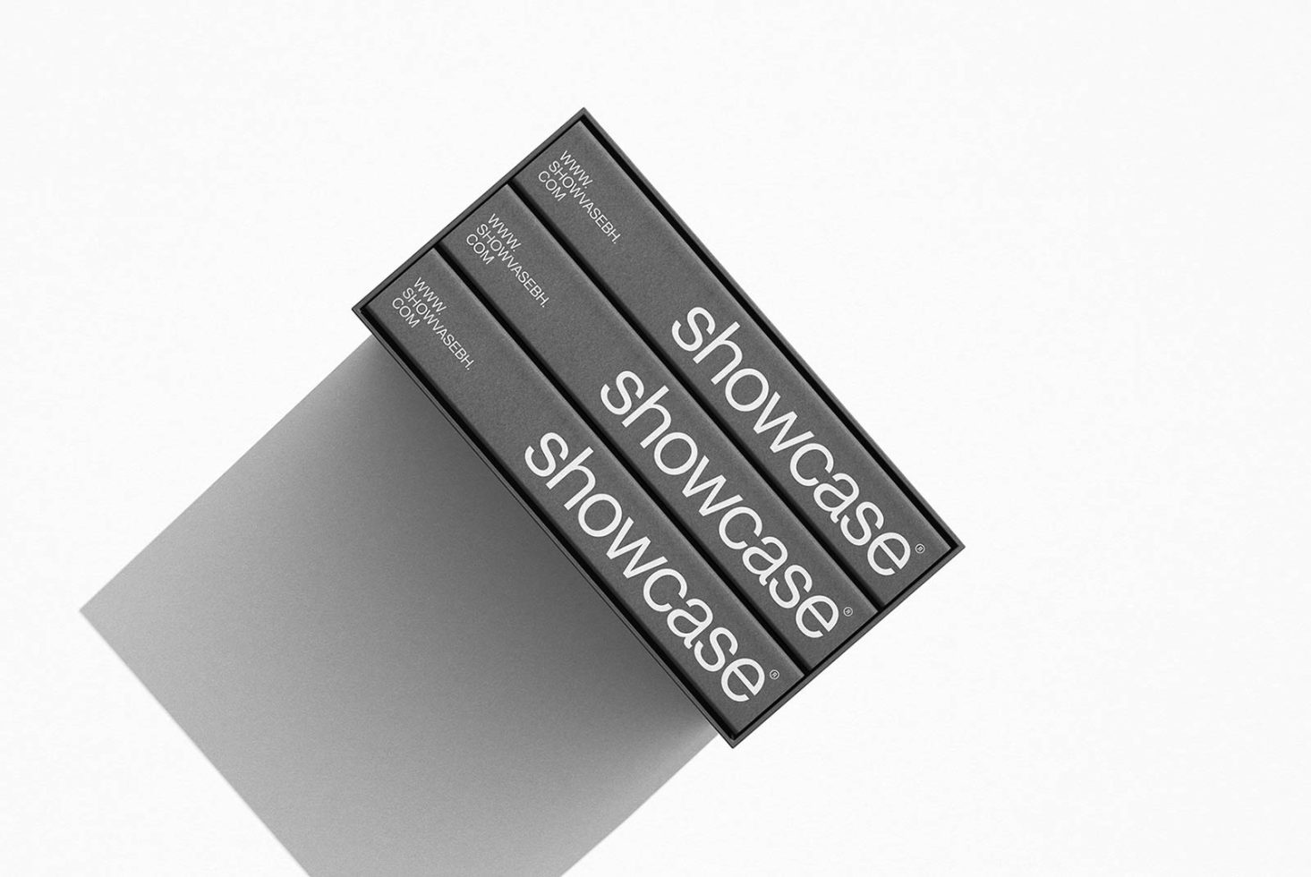 Three-tiered black boxes with the word showcase in elegant font, cast shadow on white background, ideal for mockup presentations by designers.